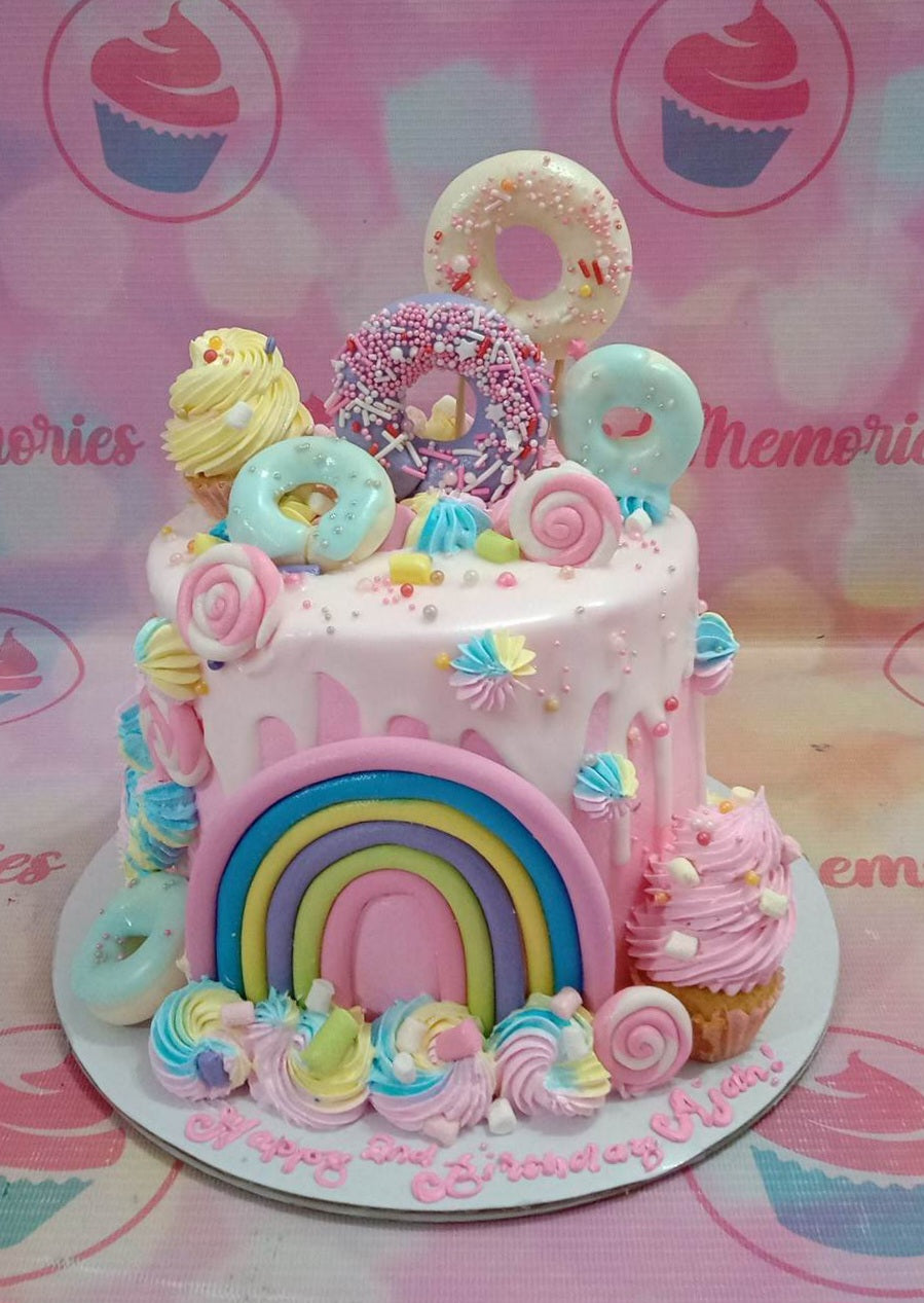 This stunning Rainbow Cake is the perfect way to celebrate any occasion! It features an array of bright colors, with a white drip and rainbow donuts on top. Additional decorations include clouds, ice cream, candyland, and more. It's sure to stand out with its colorful and vibrant design. Enjoy this custom cake for your next birthday!