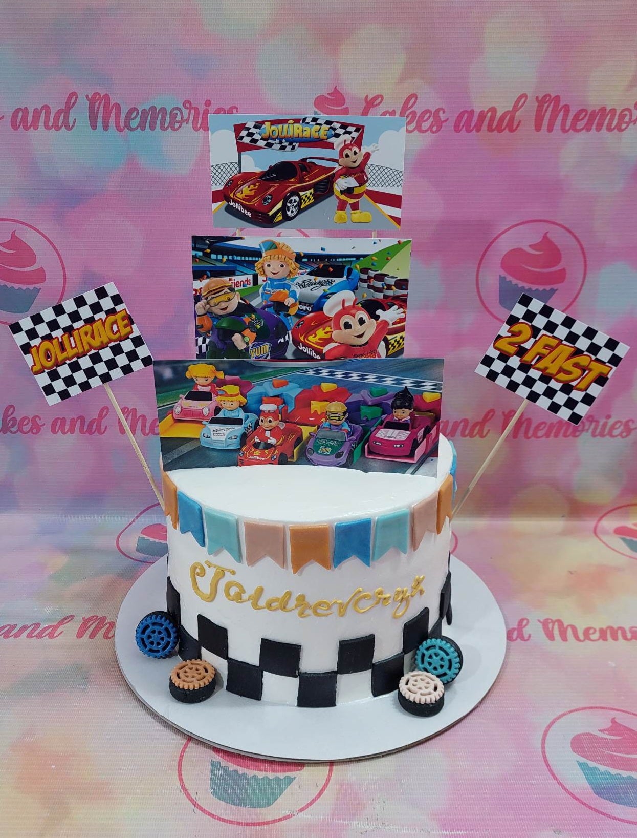 .

This custom decorated cake features an exciting racing checkered flag design and features Jolibee with his friends Hetty and other Fastfood Pinoy characters. The cake is white with vibrant colors, perfect for a birthday celebration. All decorations are of excellent quality.