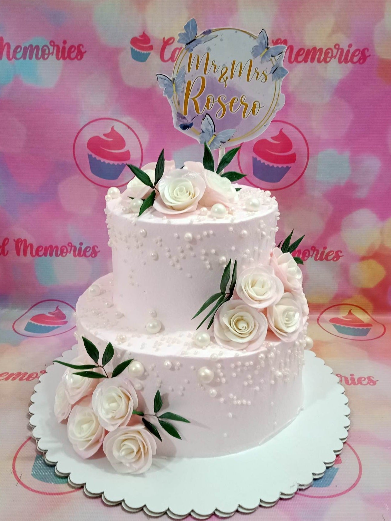 This beautiful, custom-decorated wedding cake is perfect for any special occasion. It features delicate pink roses, pearl dragees, and a butterfly topper, making it ideal for 20th, 30th, 40th, 50th, and 60th wedding anniversaries, birthdays, and weddings. Show your loved one your special feelings and make a wonderful celebration with this cake.