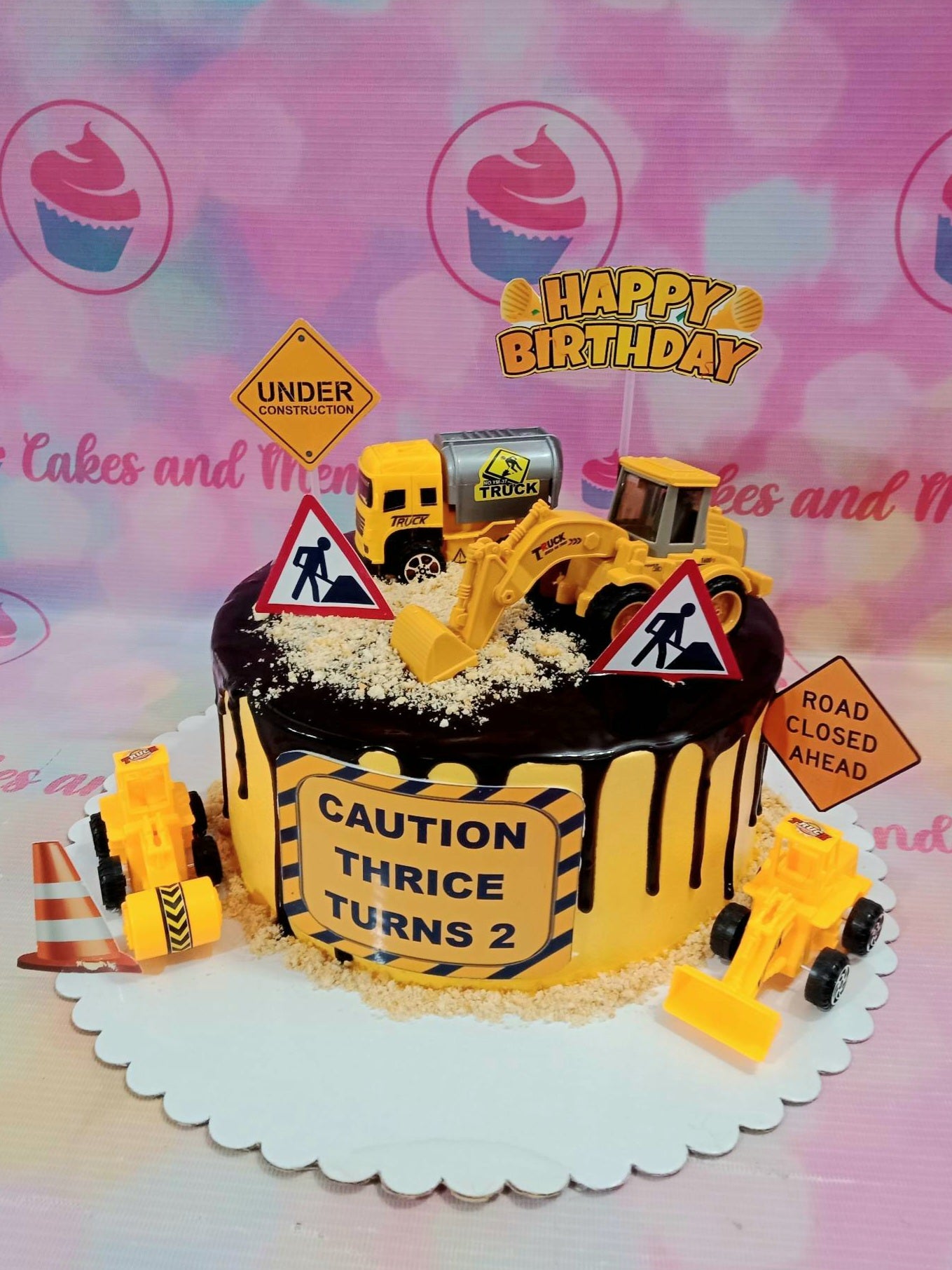 This beautiful custom construction cake is perfect for any birthday celebration. It features a realistic yellow truck with buildable toys and is finished off with a delicious chocolate drip. Each cake is handcrafted and customized to your specifcations.