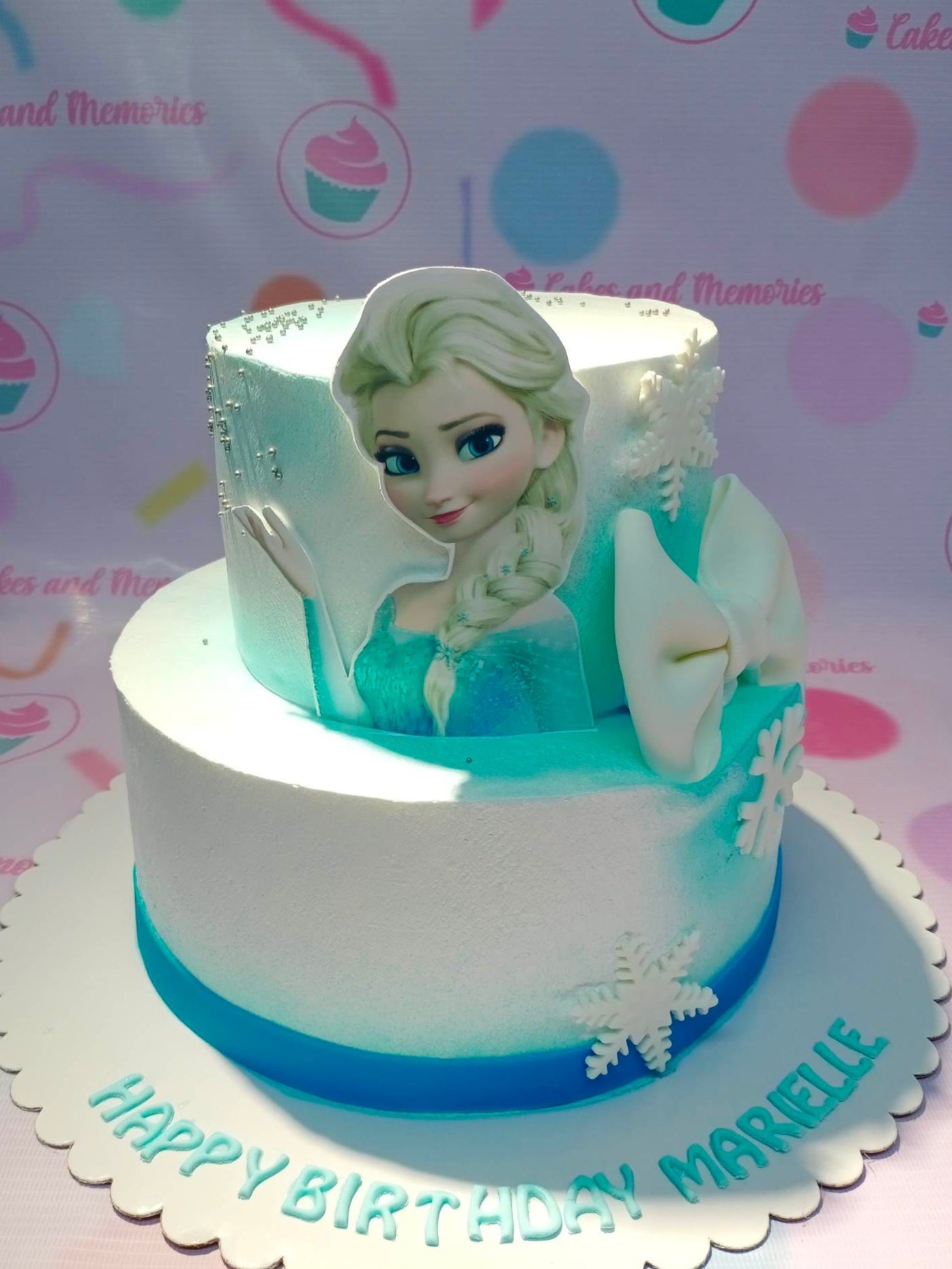 This beautiful custom decorated cake is perfect for any Frozen themed birthday party. It has a white base and is adorned with blue snowflakes and images of Elsa, Anna and Olaf. The quality of the decorations is unbeatable, making it the perfect choice for kids and Disney princess fans.